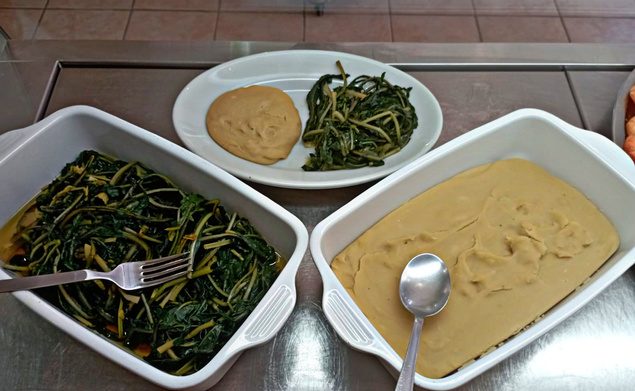 Fave e cicorie di Al Gusto Giusto: purè e verdure in pirofile bianche su banco d'acciaio, con un piatto ovale