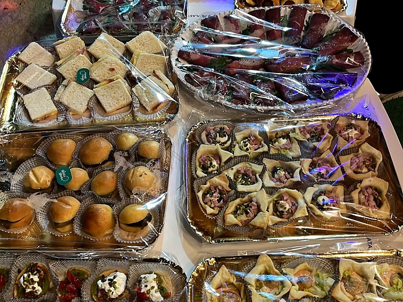 Vassoi dorati con tramezzini, panini al latte, cestini di sfoglia e rotolini di bresaola di Al Gusto Giusto